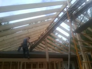 Rafters going up over a new addition with a worker on the wall in Salisbury