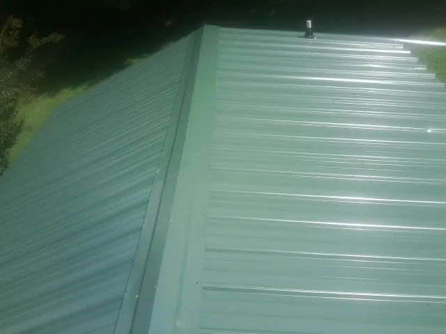 New green metal panels meeting at the ridge of a roof — Flat Roof Repair work by our crew in Salisbury